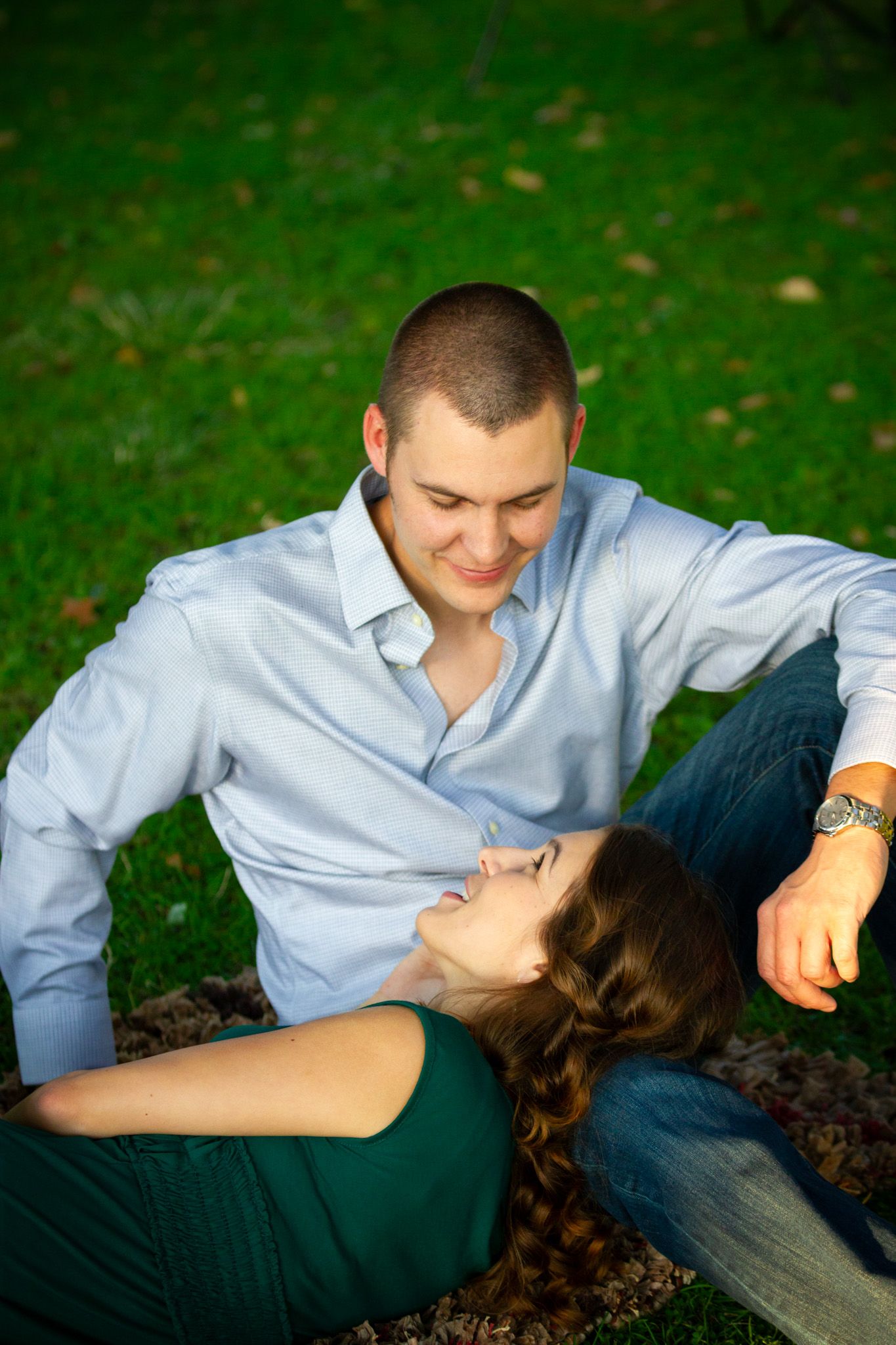 Couple relaxing on grass during outdoor photo session with romantic pose.