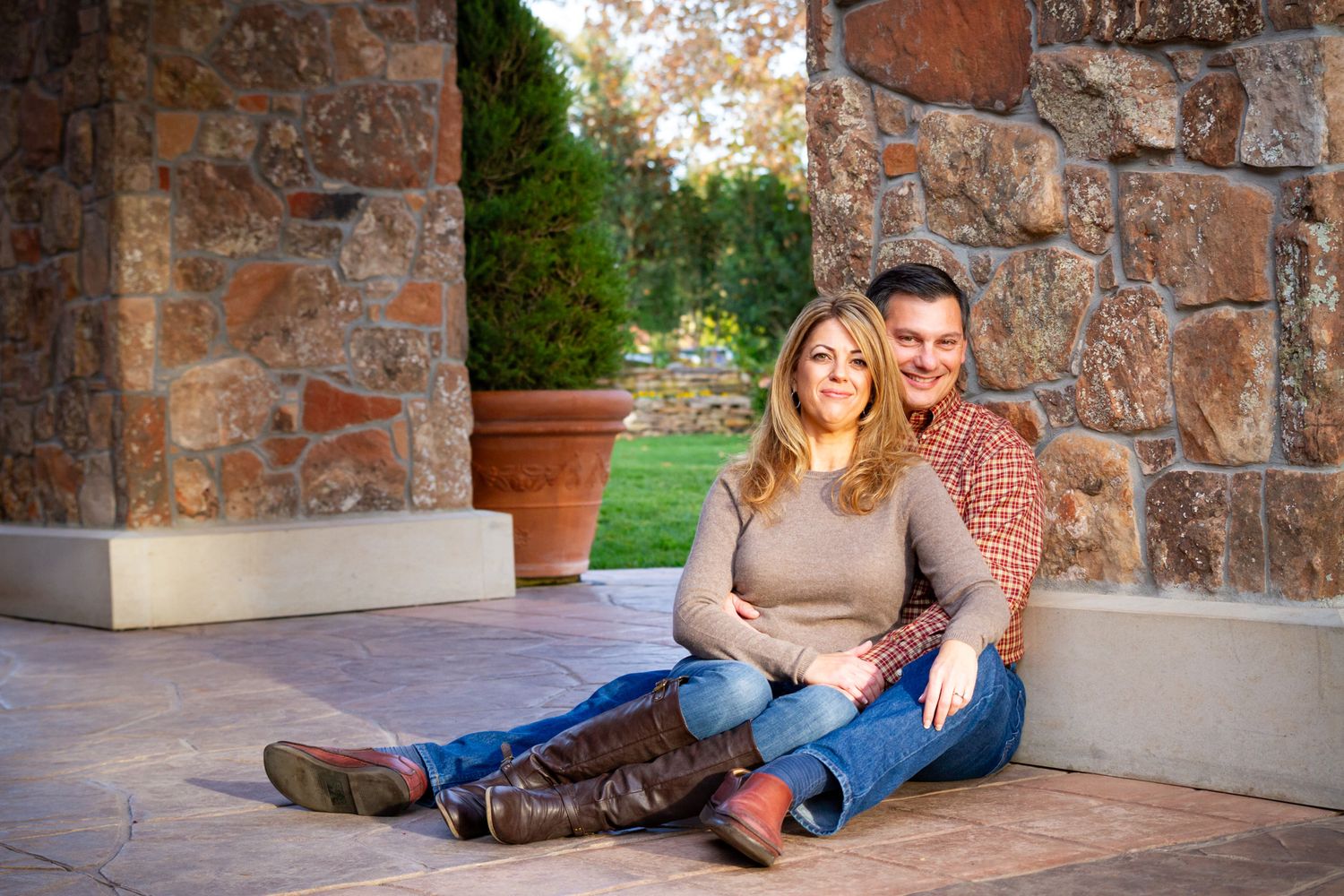 Casual engagement photos taken against rustic stone wall backdrop.