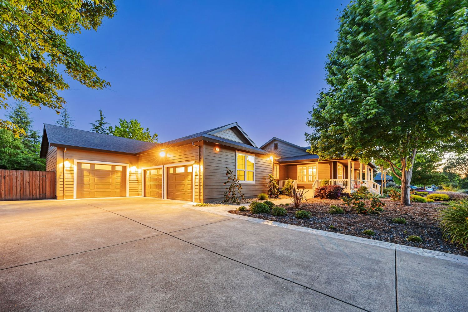 Elegant modern home with three-car garage and professionally landscaped driveway at twilight.