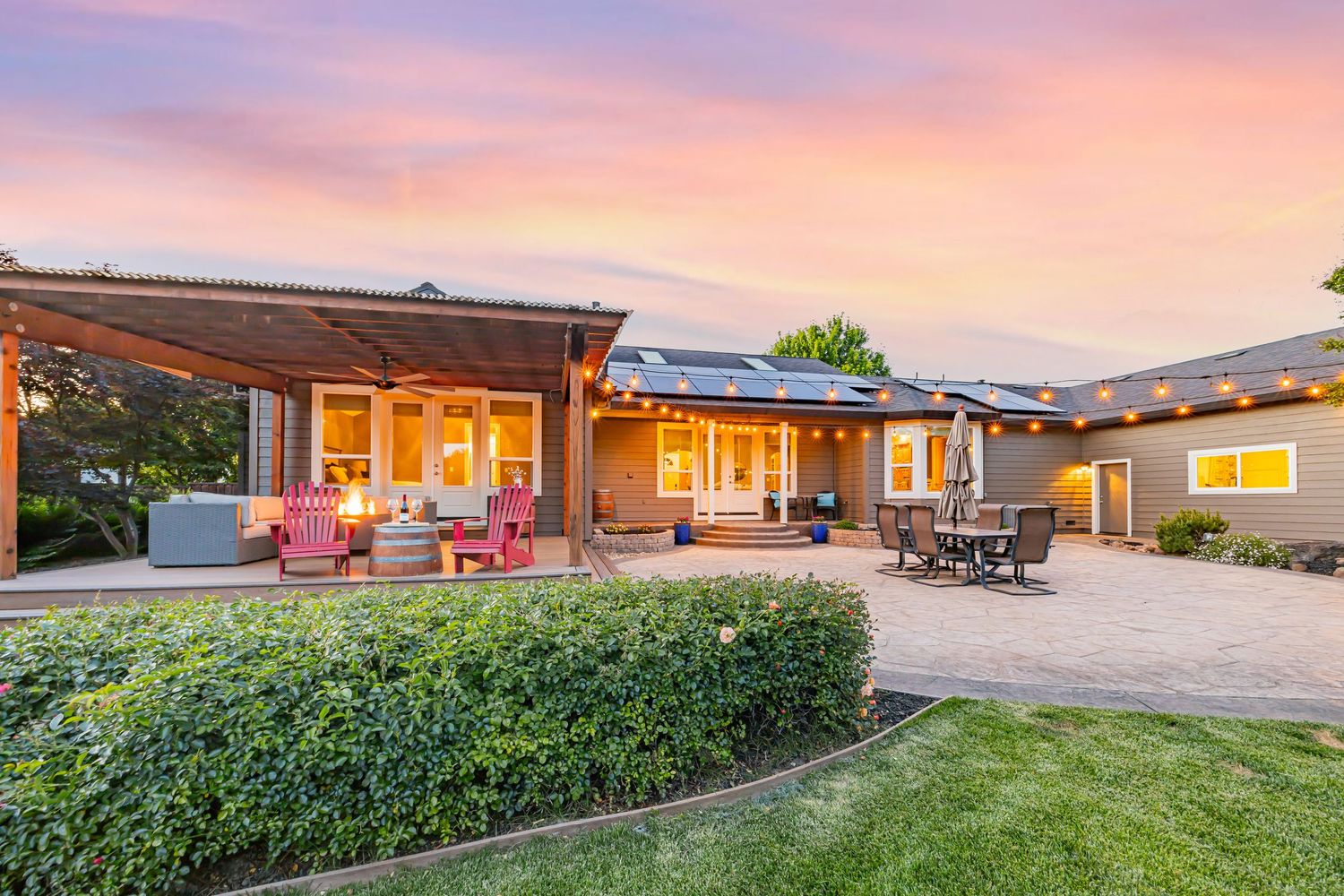 Modern single-story home with extensive patio space and landscaping illuminated at sunset.