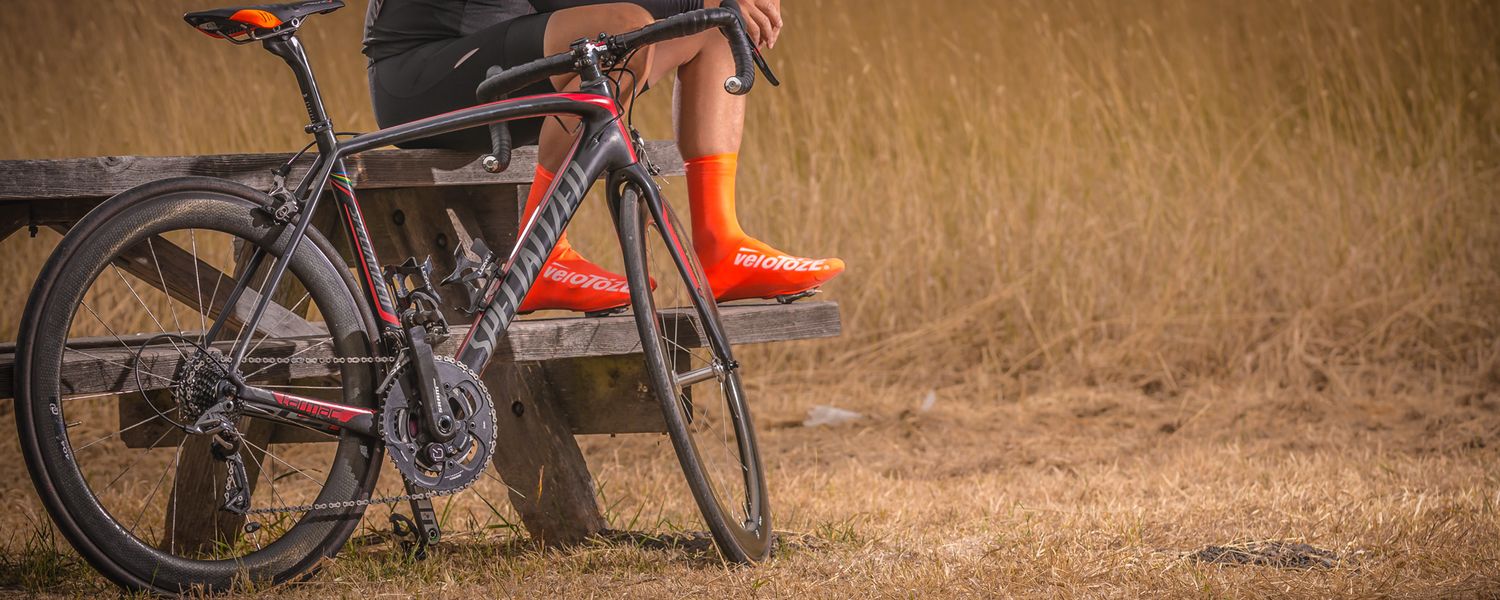 Red racing bicycle parked against dry grass field background.