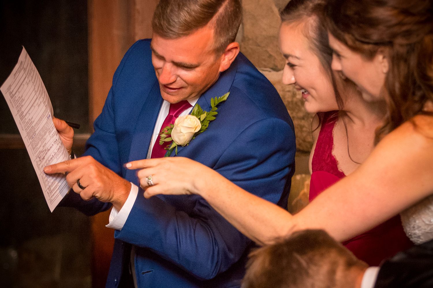 People in formal attire share a laugh while looking at papers together.