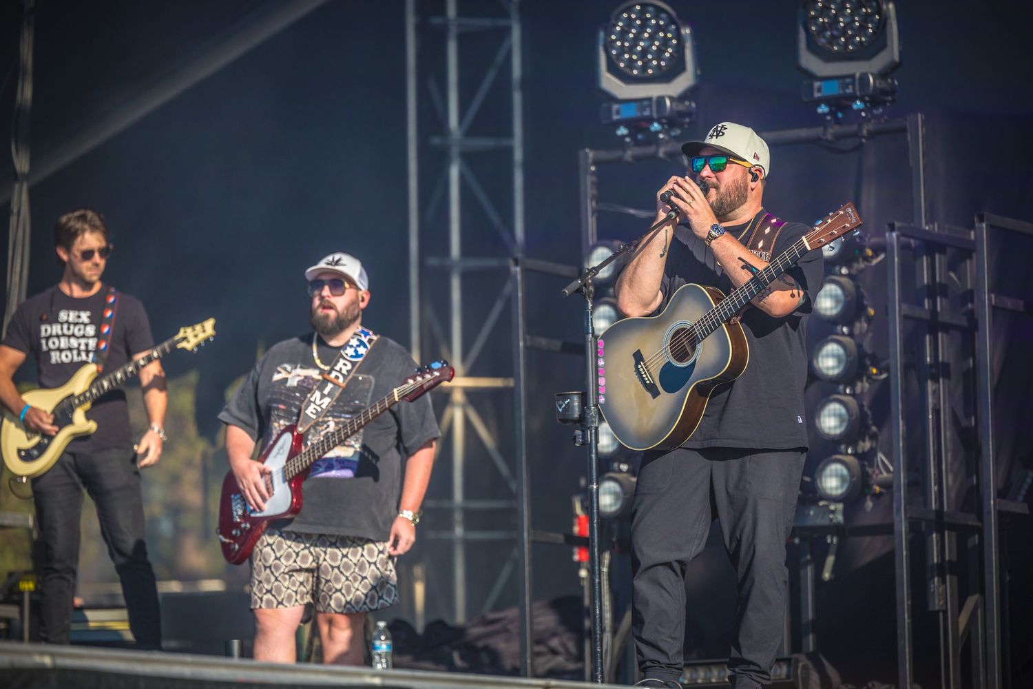 Musicians performing on stage with guitars during a live concert with professional lighting setup.