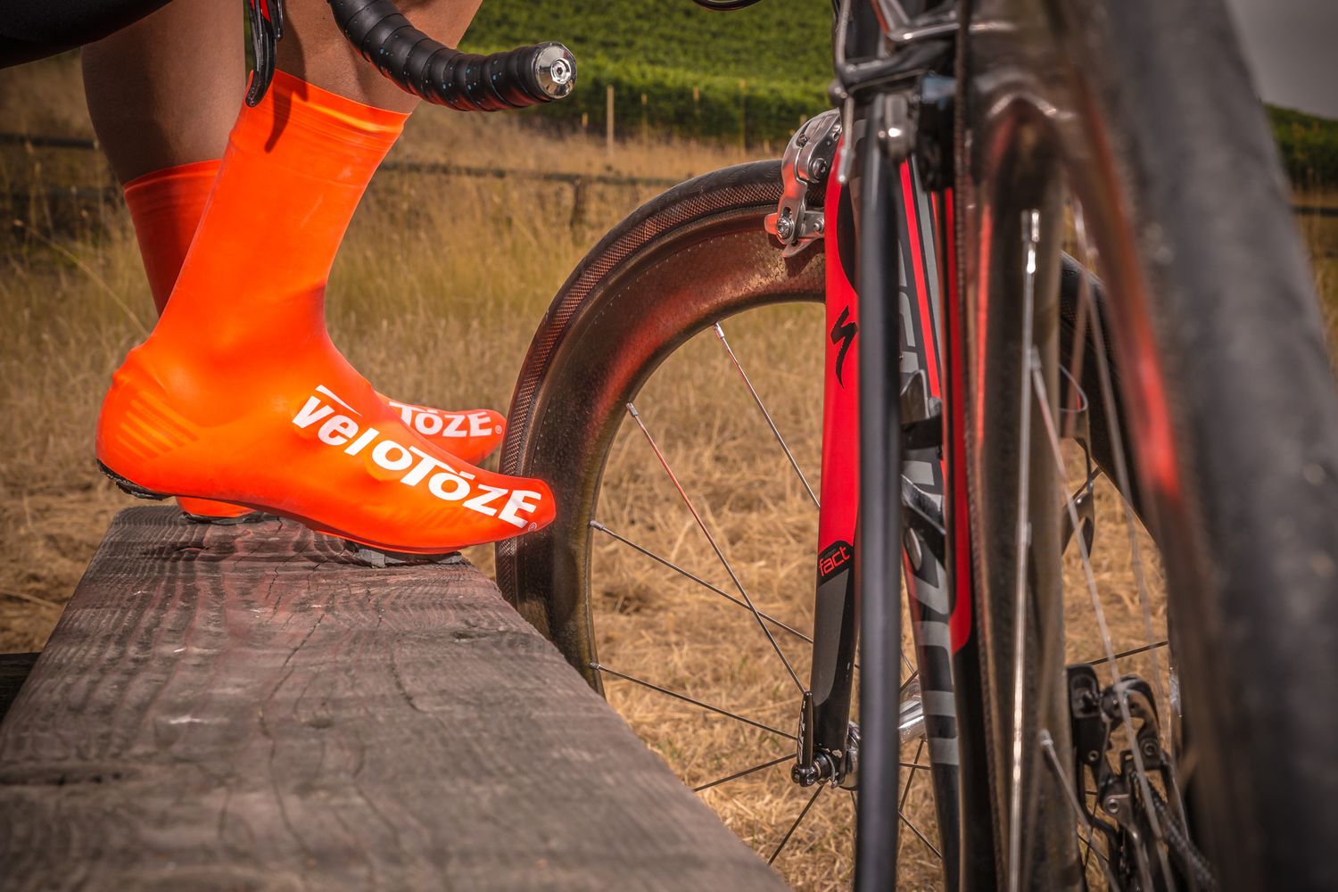 Detail shot of bright orange cycling shoes next to black road bike frame.