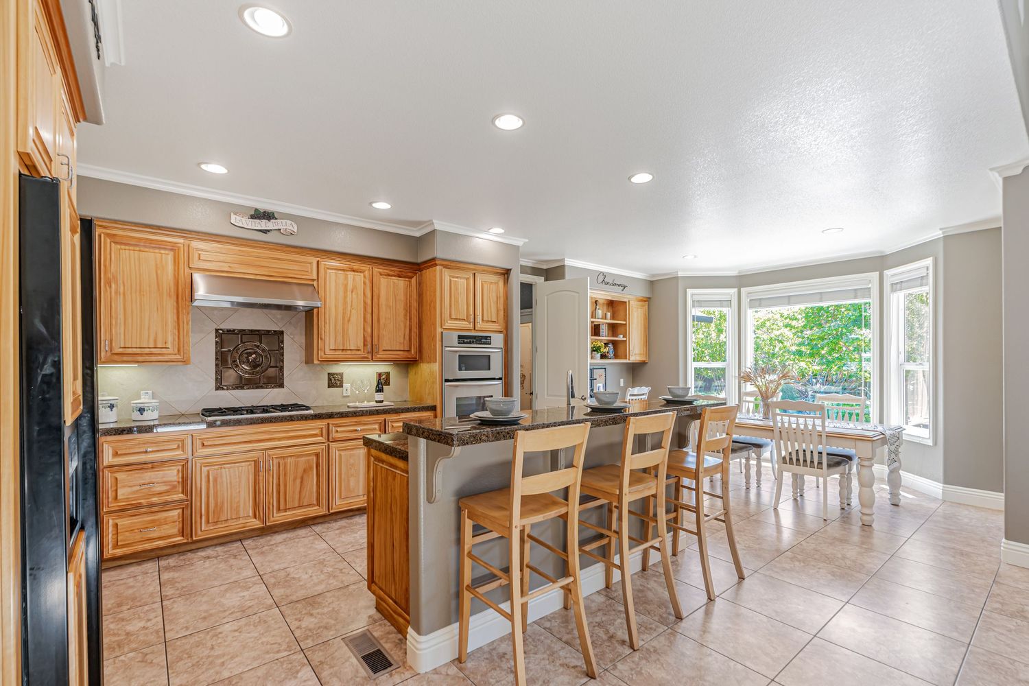 Modern kitchen with honey oak cabinets, breakfast bar, and stainless steel appliances.