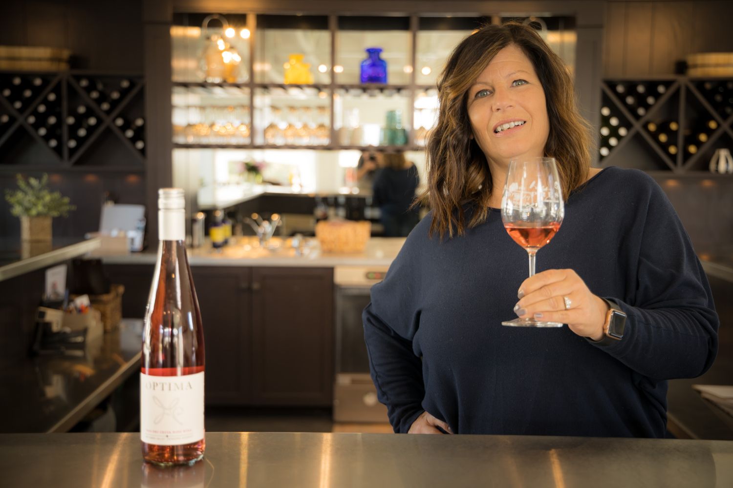 A wine tasting scene in an upscale bar with shelved bottles in the background.