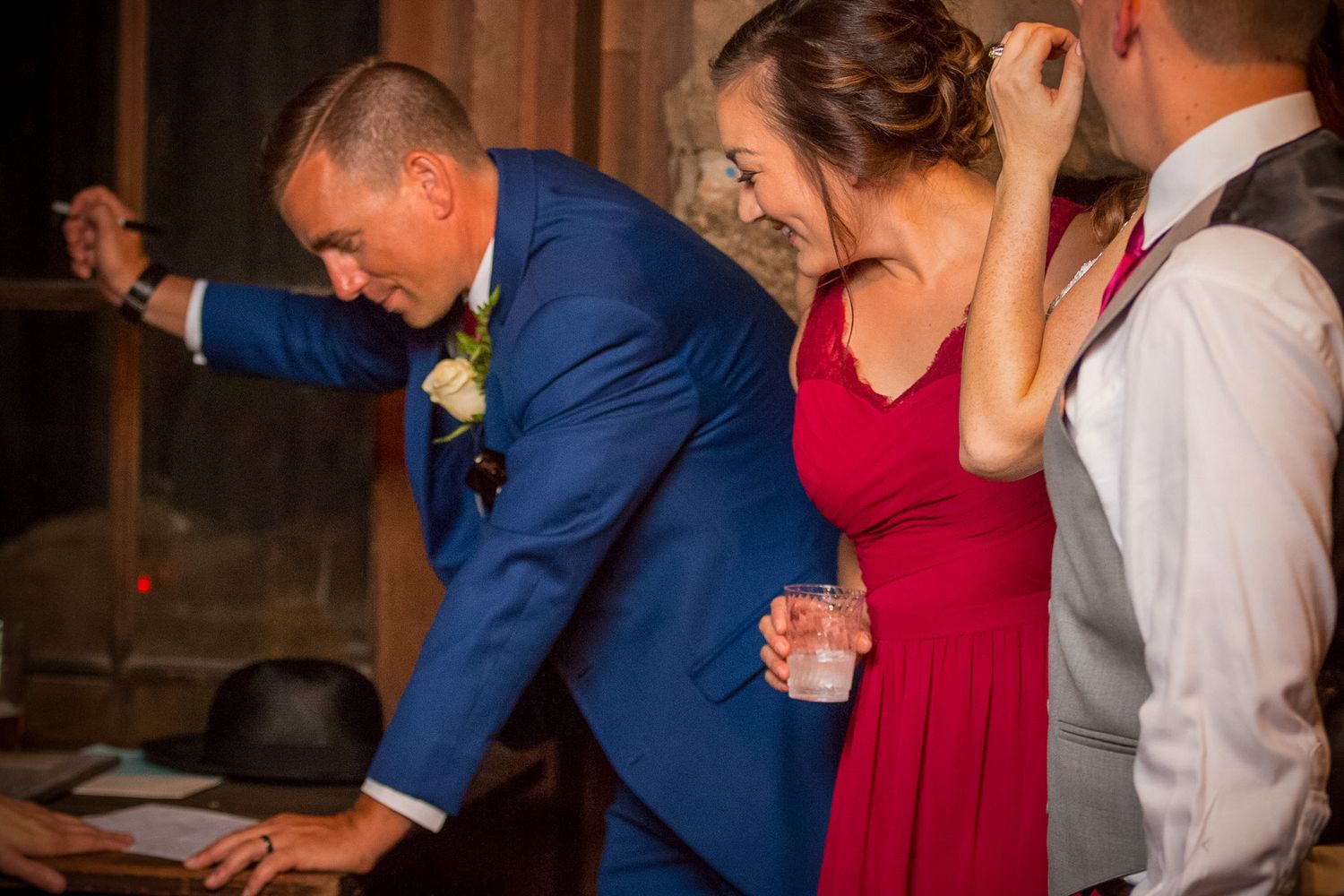 Three people react expressively while reading something at a formal event.