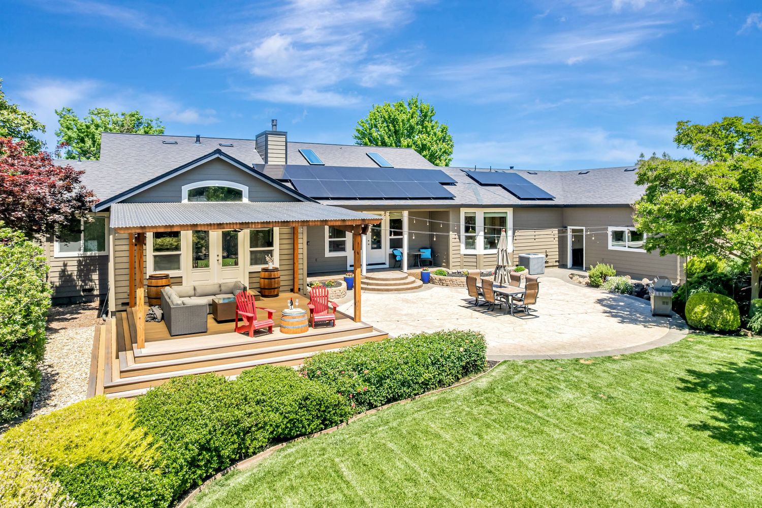 Modern ranch home with covered patio, outdoor furniture, and solar panels on the roof.
