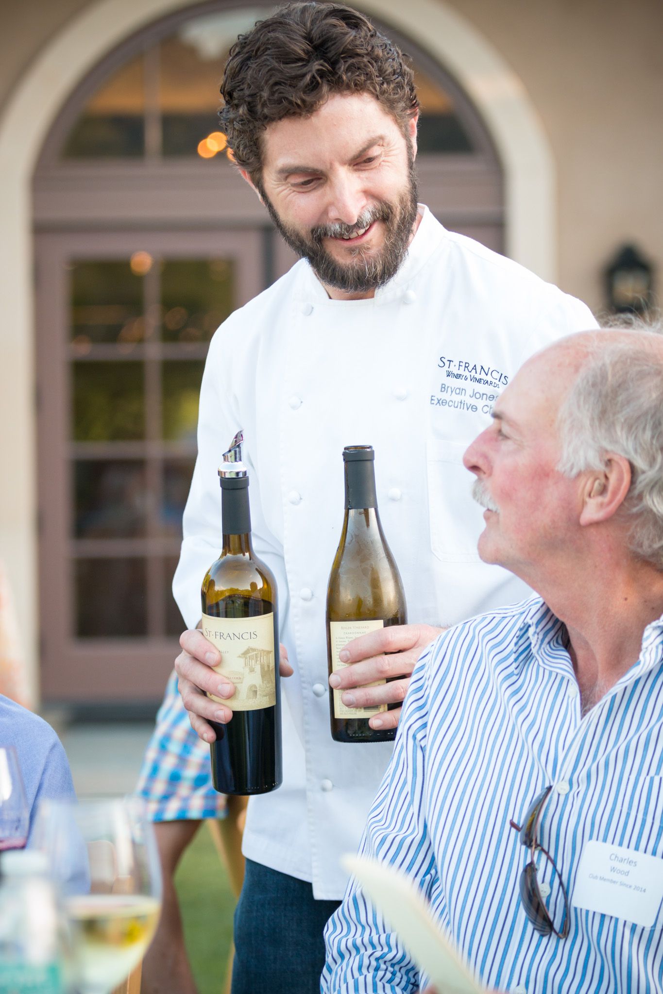 Wine tasting event showing bottles being presented at an outdoor gathering.