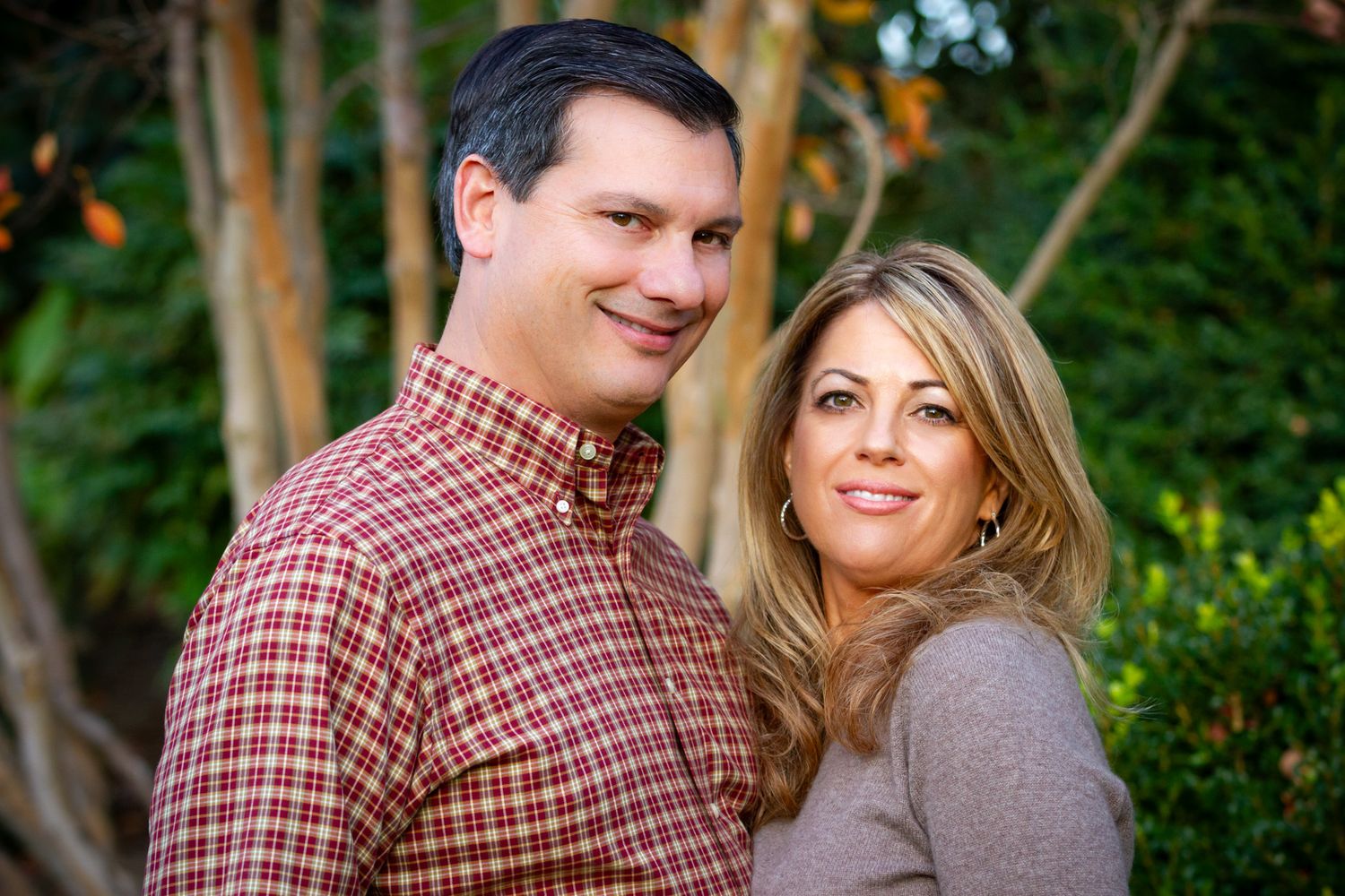 Close up portrait of couple smiling together in garden with natural lighting.