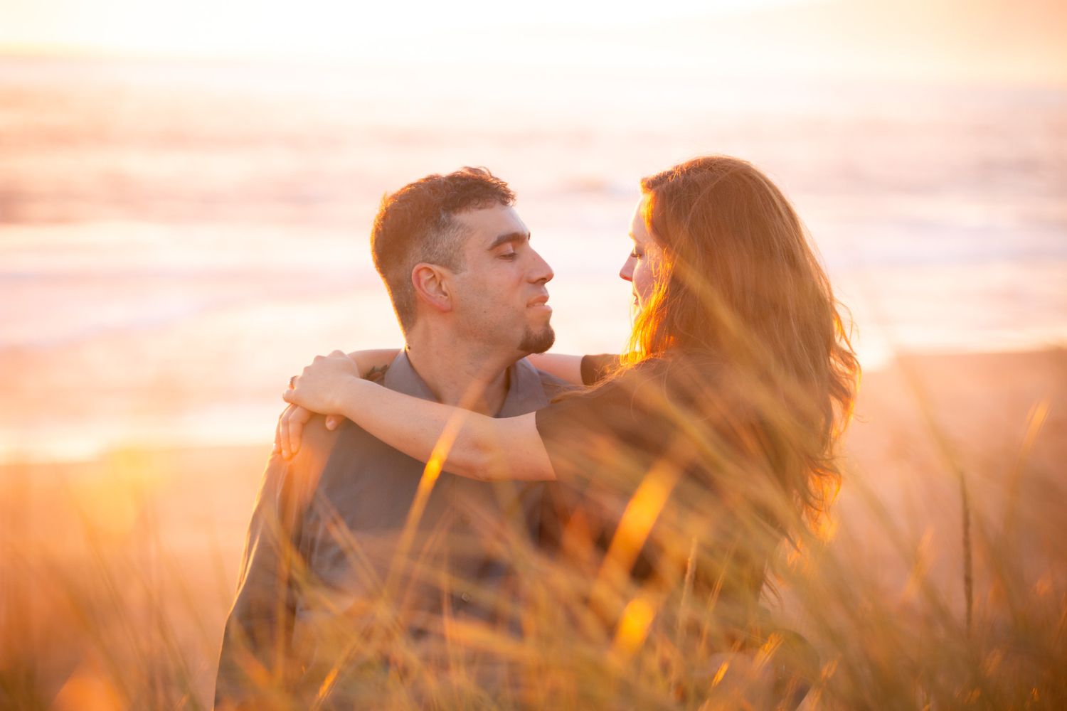 A loving couple shares an intimate moment in a sun-drenched field at golden hour.