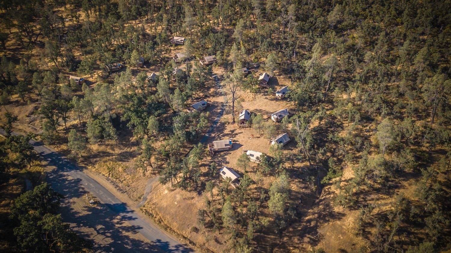 Aerial shot of resort buildings scattered among trees in a mountainous landscape.