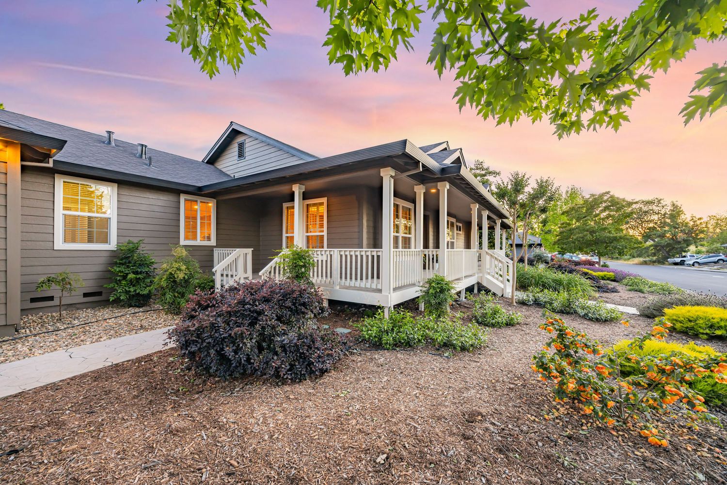 Gray craftsman home with white trim and covered porch surrounded by drought-resistant landscaping.