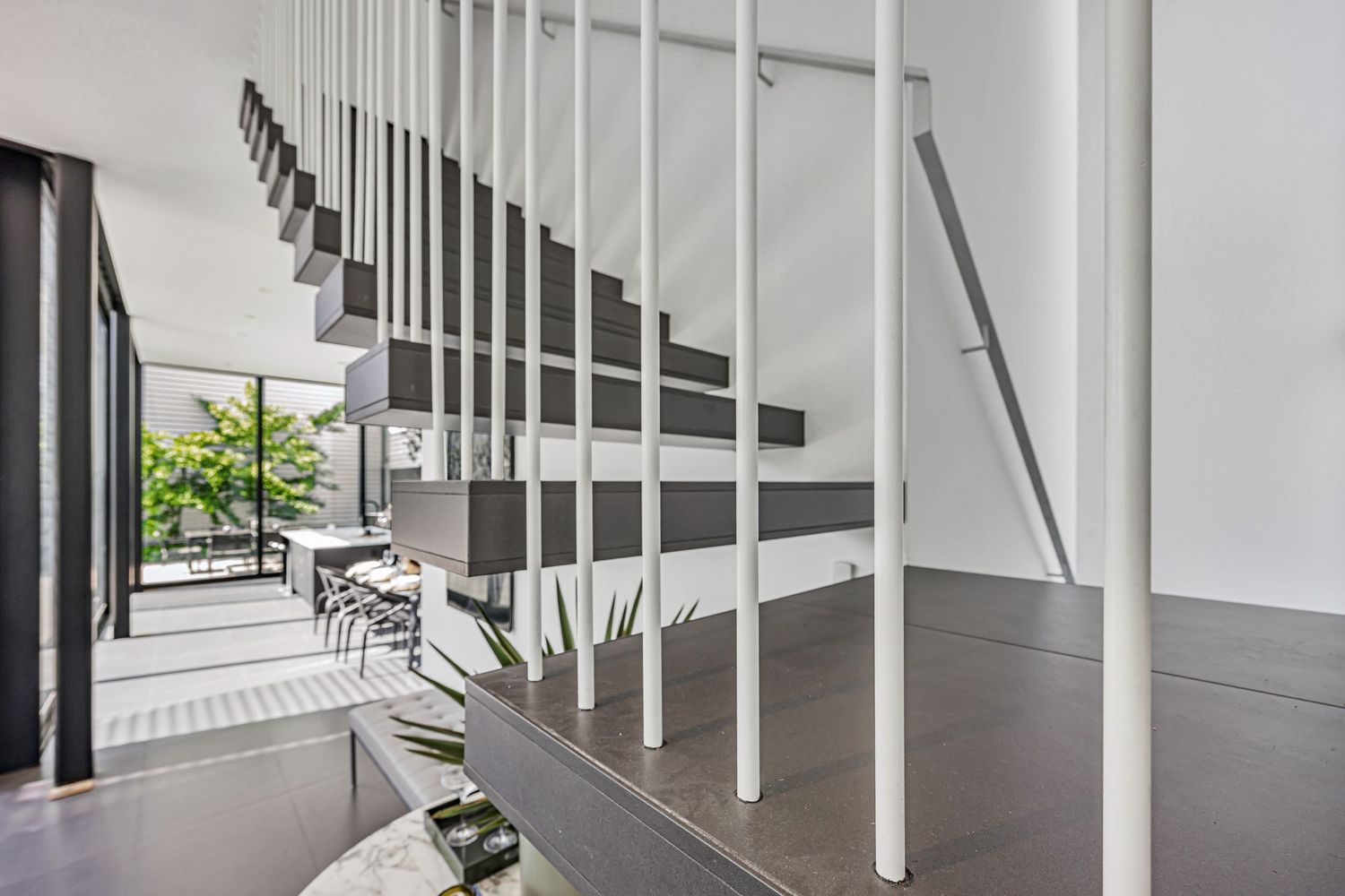 Contemporary white staircase with vertical metal railings in a modern home.