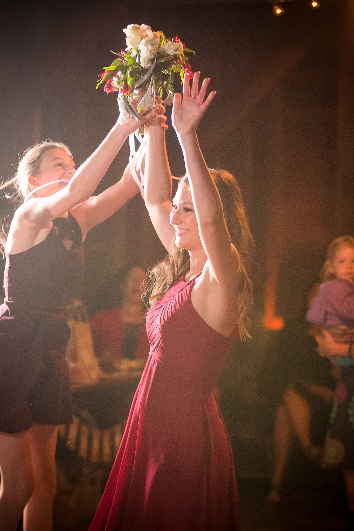 Women reach for a bouquet being tossed during a wedding celebration.