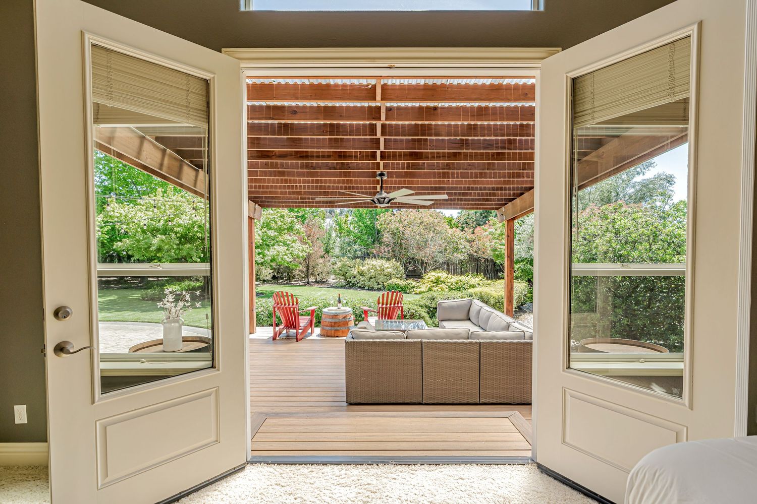 French doors opening to outdoor patio with comfortable seating and garden views.