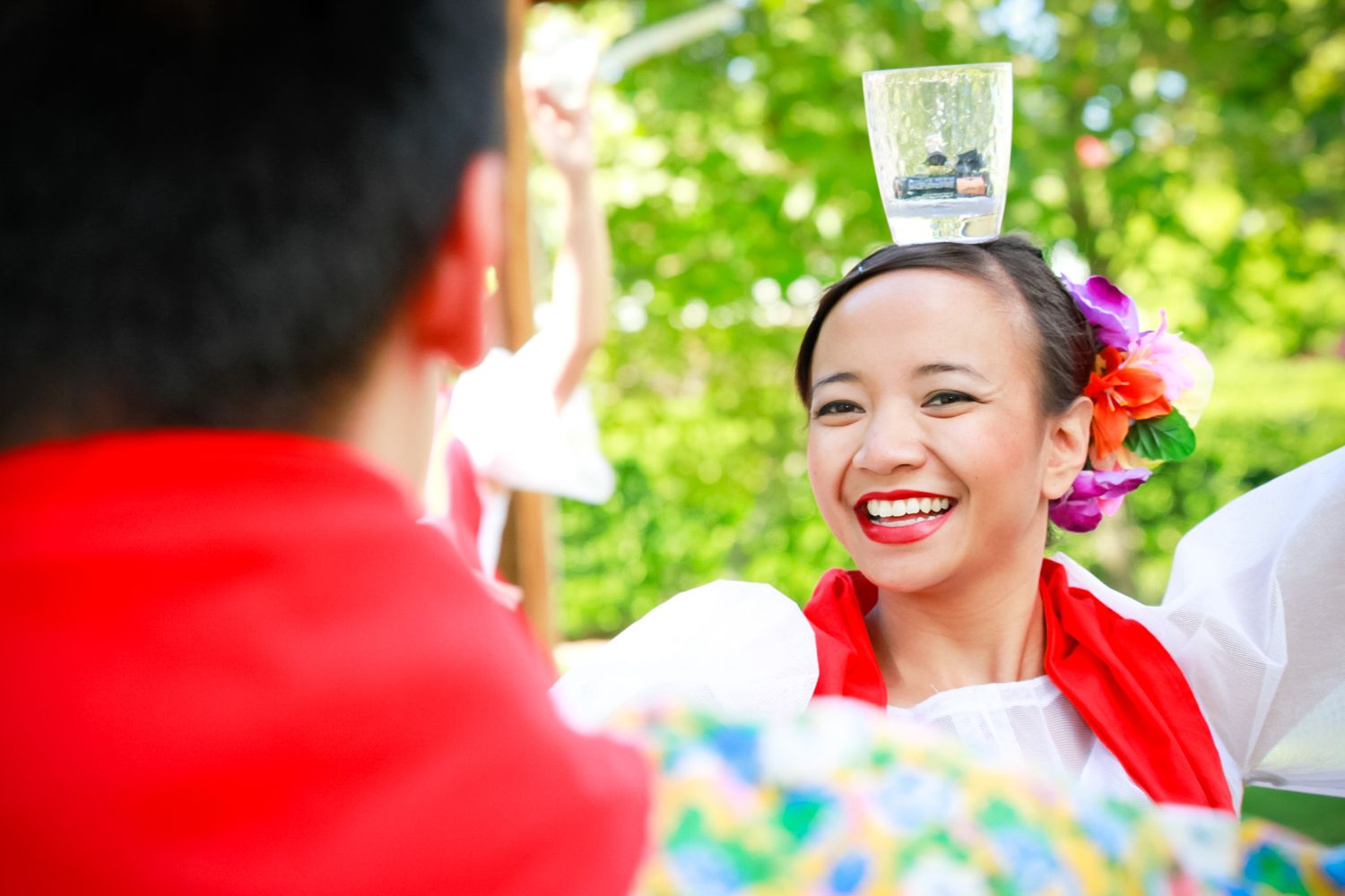 Festive outdoor celebration with traditional dancers in bright red and white costumes.