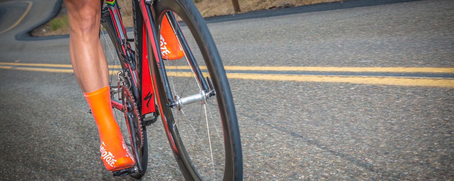 Close-up of cyclist wearing bright orange socks on road bike.