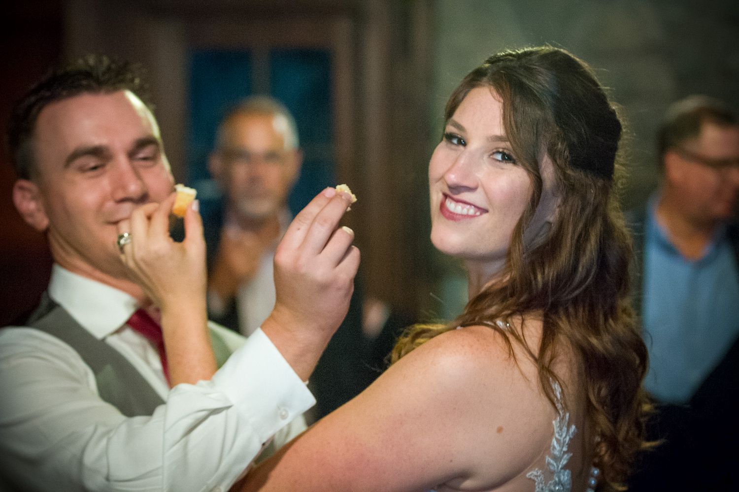 Couple sharing playful moment during wedding reception indoors.