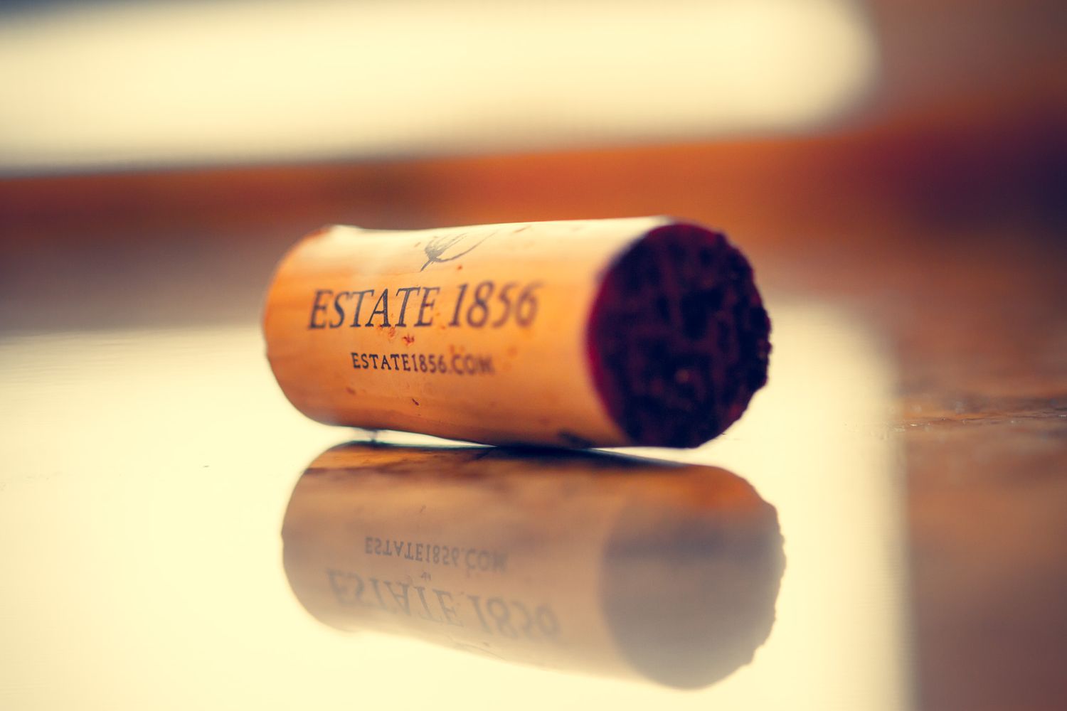 Close-up of a wine cork marked Estate 1856 reflecting on a glossy surface.