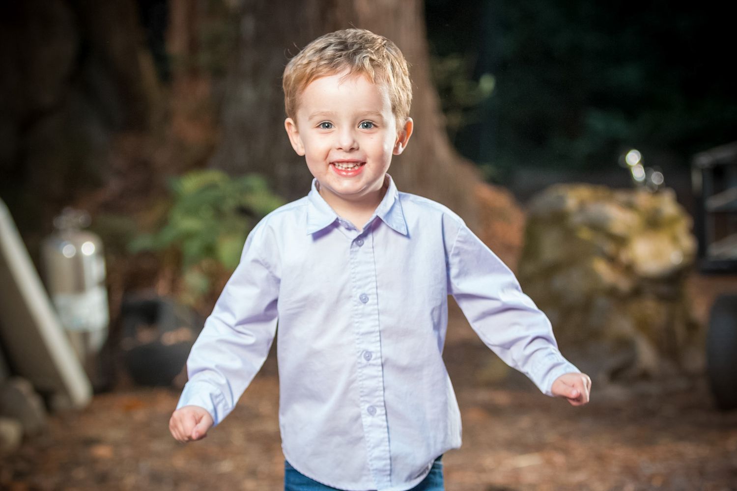Young boy in light blue shirt running and playing outdoors with a happy expression.
