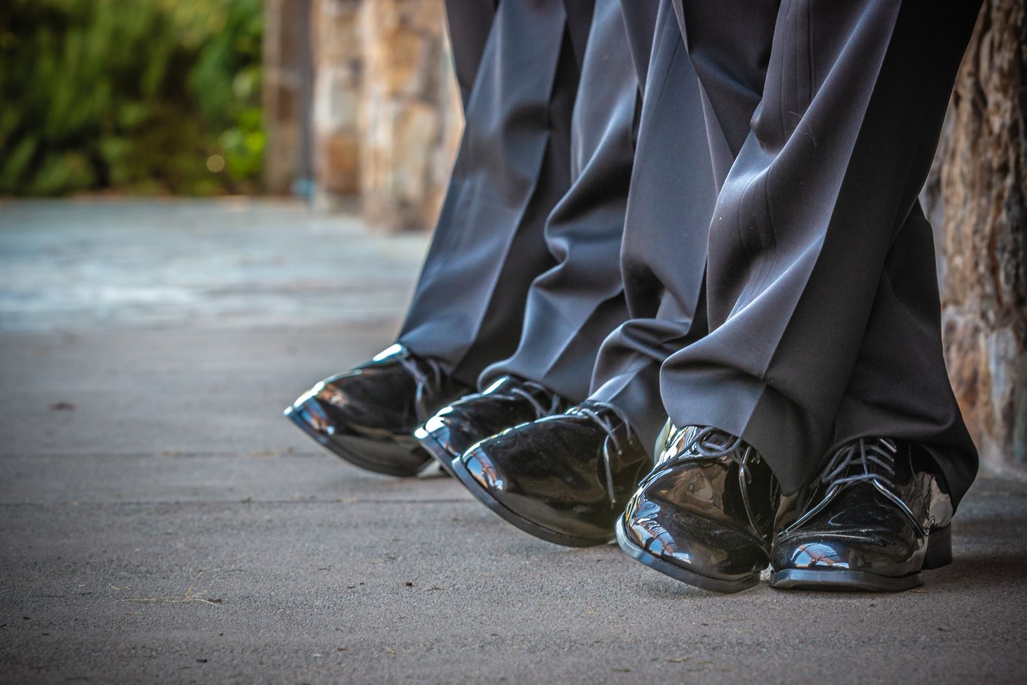 Close-up of formal dress shoes worn by multiple people standing together.