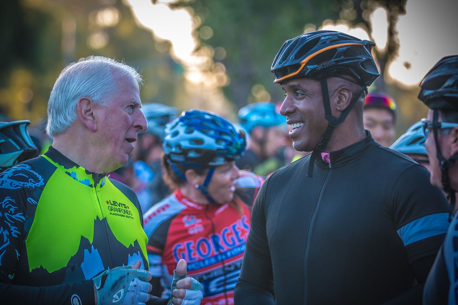 Cyclists in bright athletic gear chatting and socializing during an outdoor biking event.