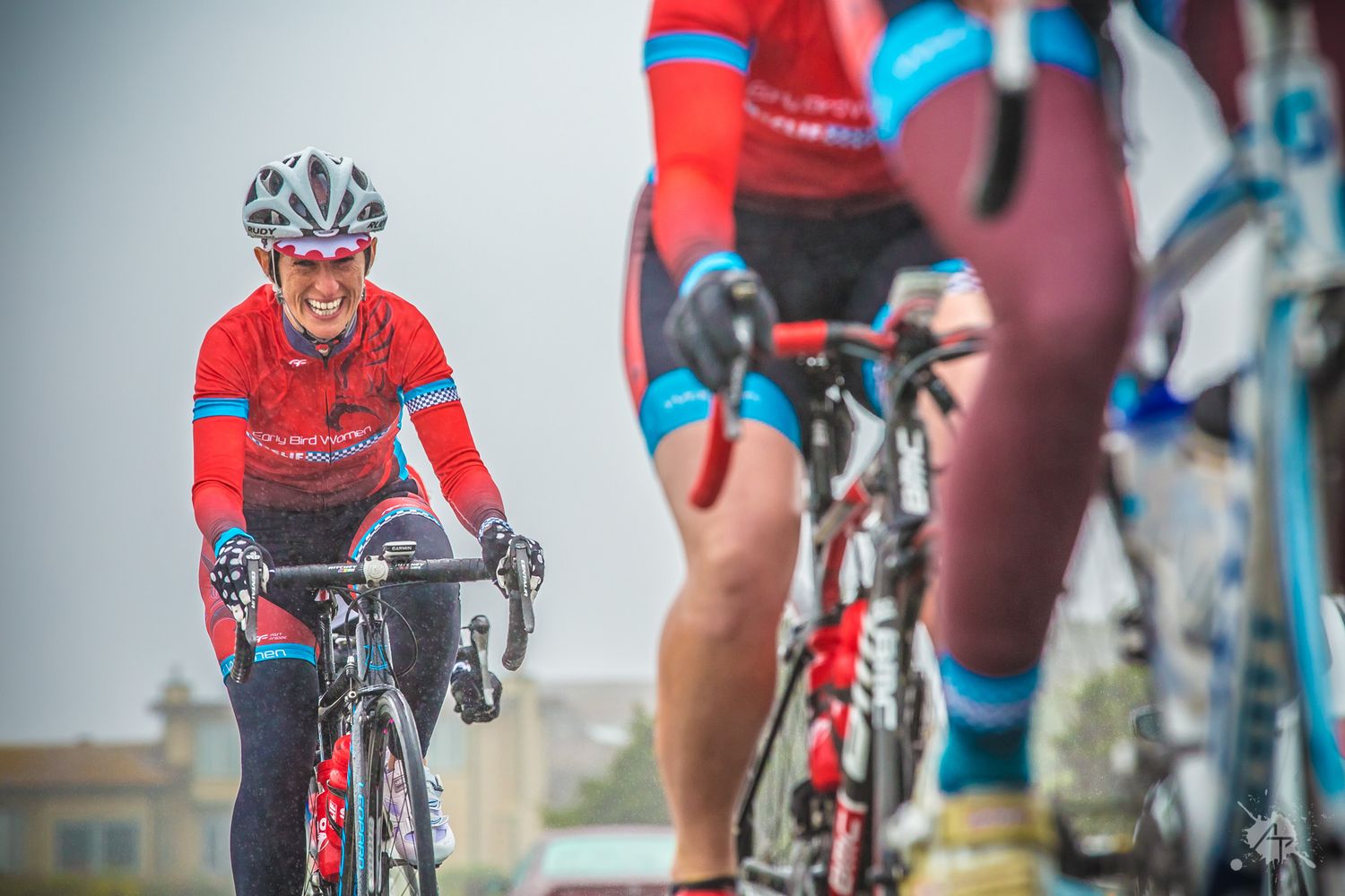Cyclists wearing red jerseys ride road bikes together during an outdoor cycling event.