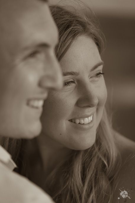 Close-up portrait of couple smiling in warm sepia tones.