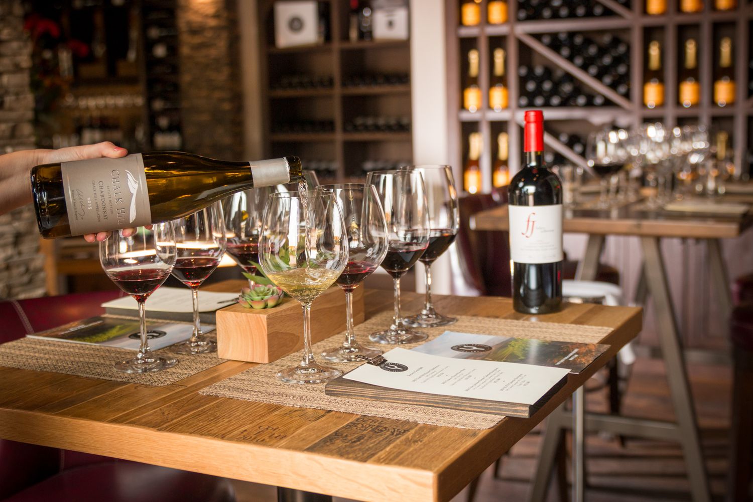 Wine tasting setup with elegant glasses and bottles in a rustic cellar setting.