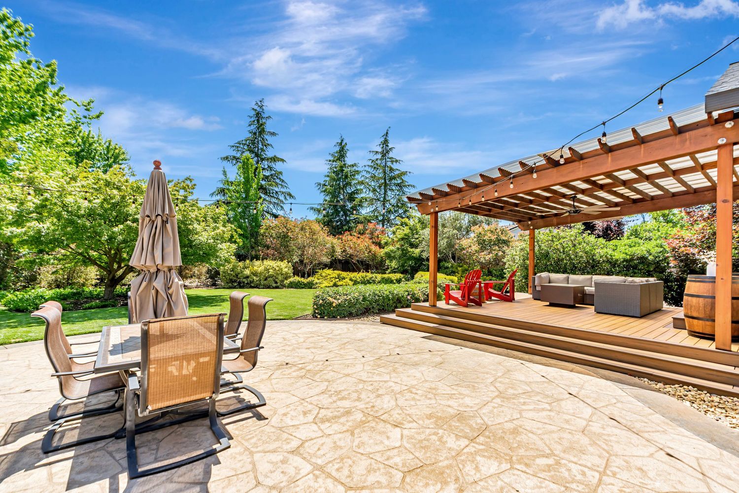 Large outdoor entertaining area with pergola and multiple seating zones on stamped concrete patio.