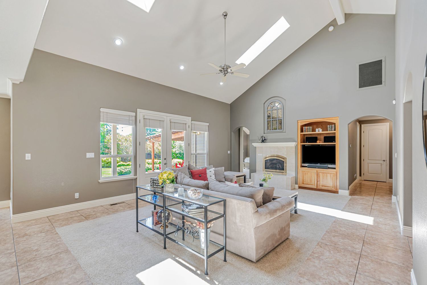 Spacious living room with vaulted ceiling, skylights, and modern furniture centered around a fireplace.