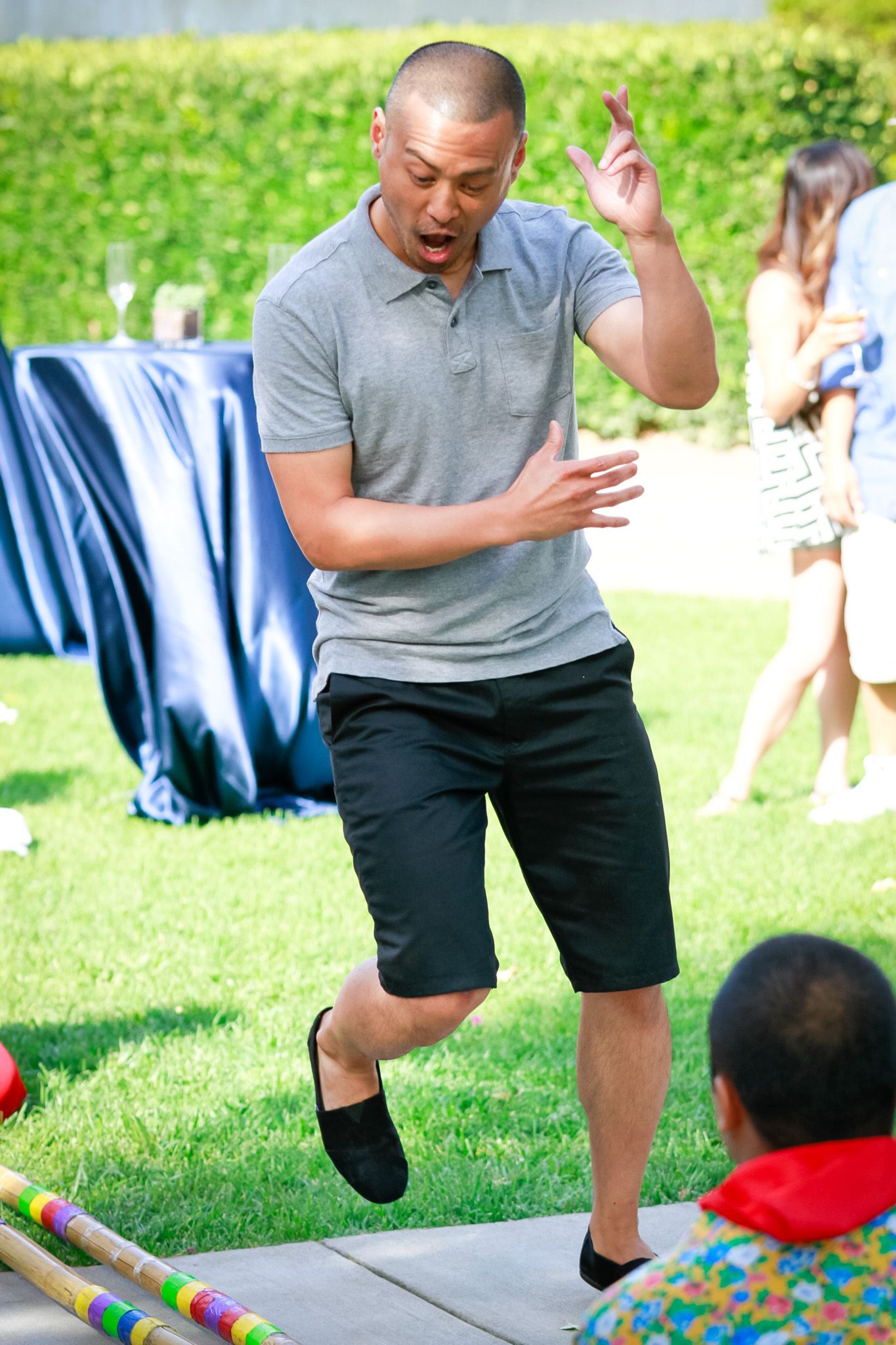 Man in grey polo shirt performing dynamic dance moves over colorful bamboo sticks.