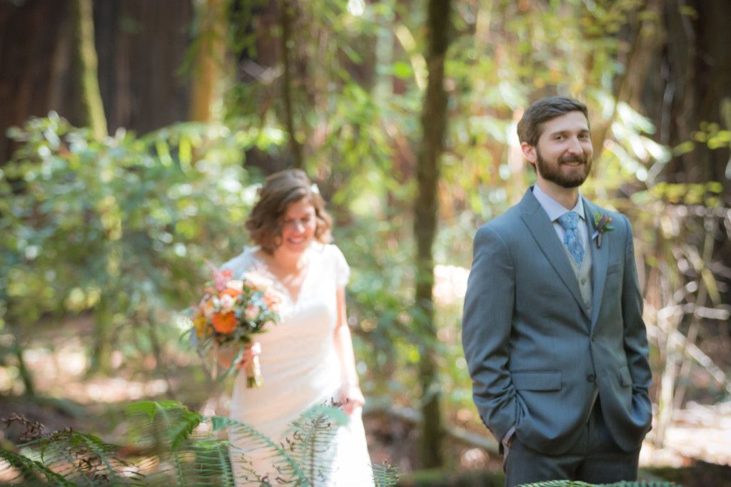 Couple stands in a sunlit forest clearing during their wedding day.