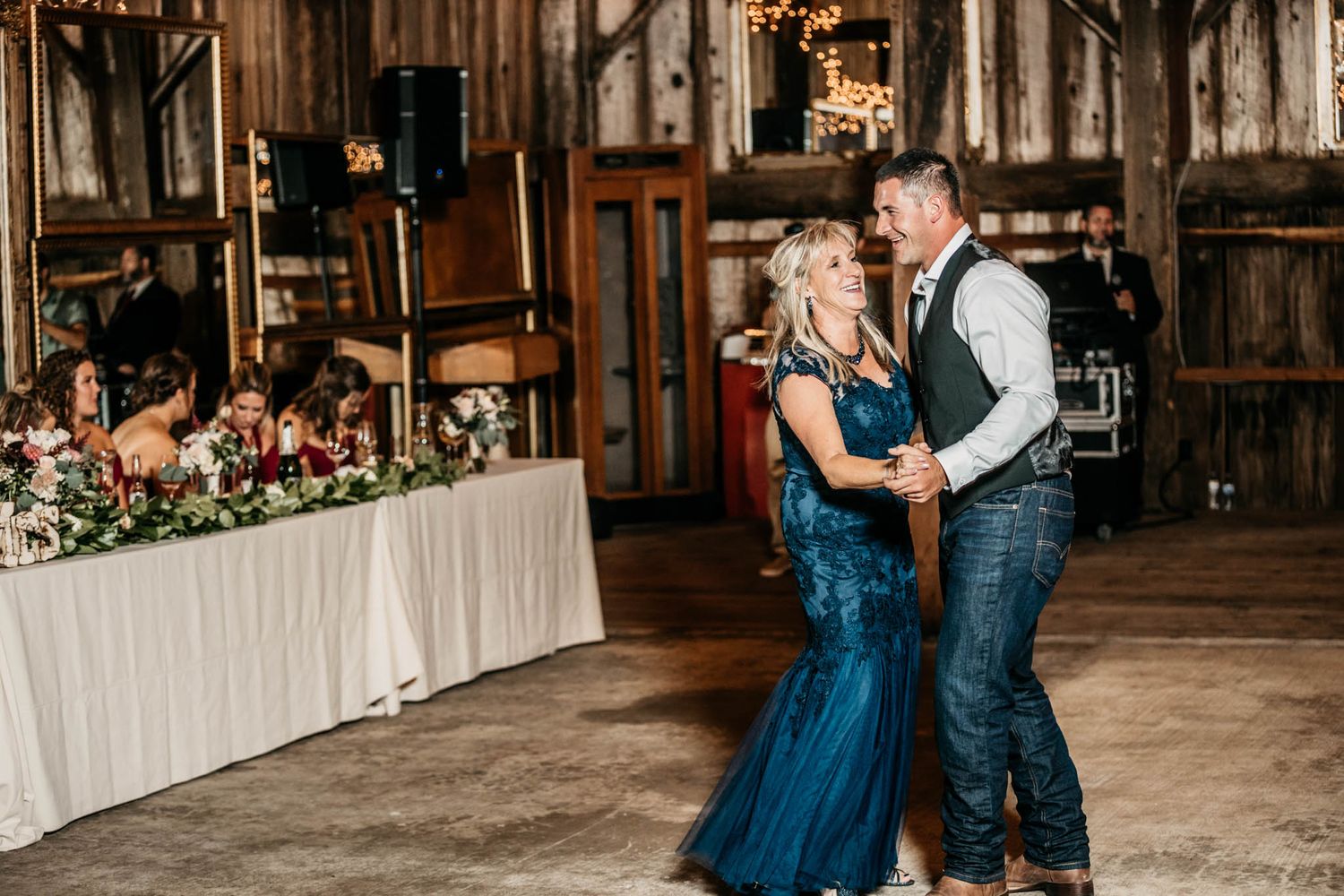 A couple dances together at a rustic barn wedding reception.
