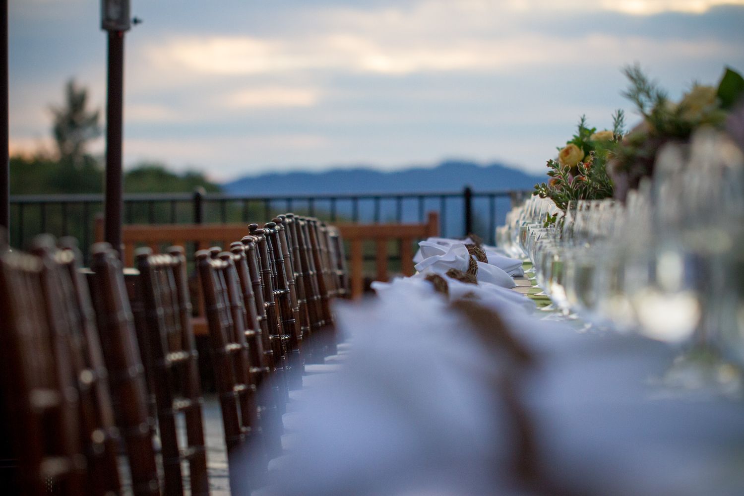 Long table set for wedding reception with mountain vista in background.