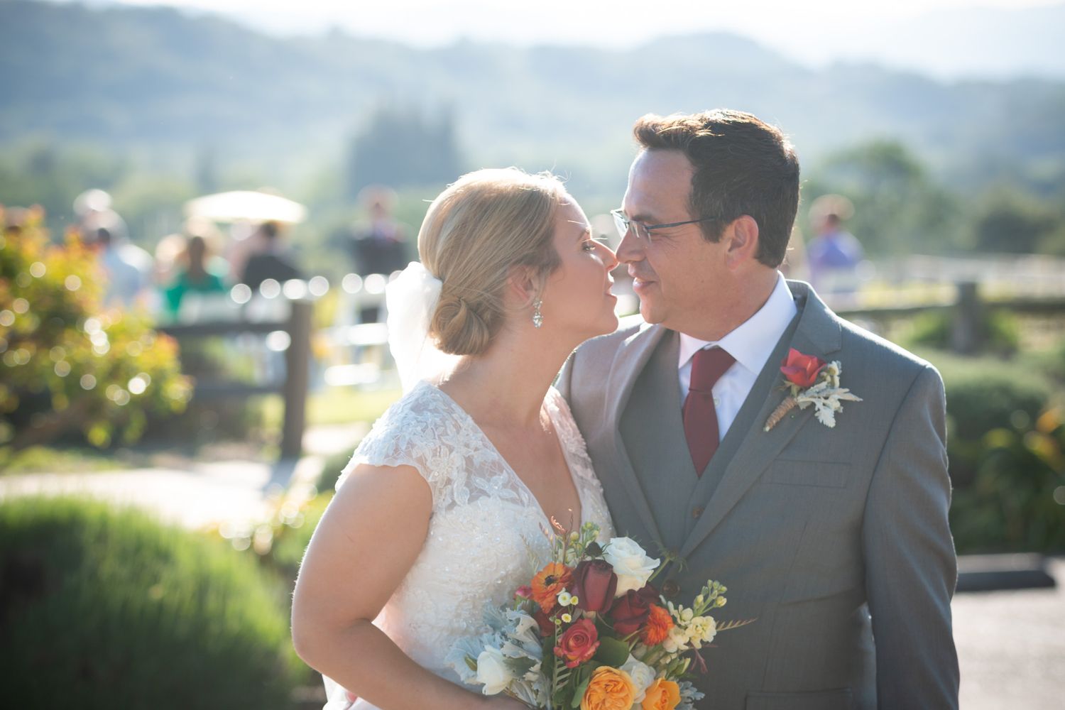 Newlyweds share an intimate moment in a sunlit garden with vibrant florals.