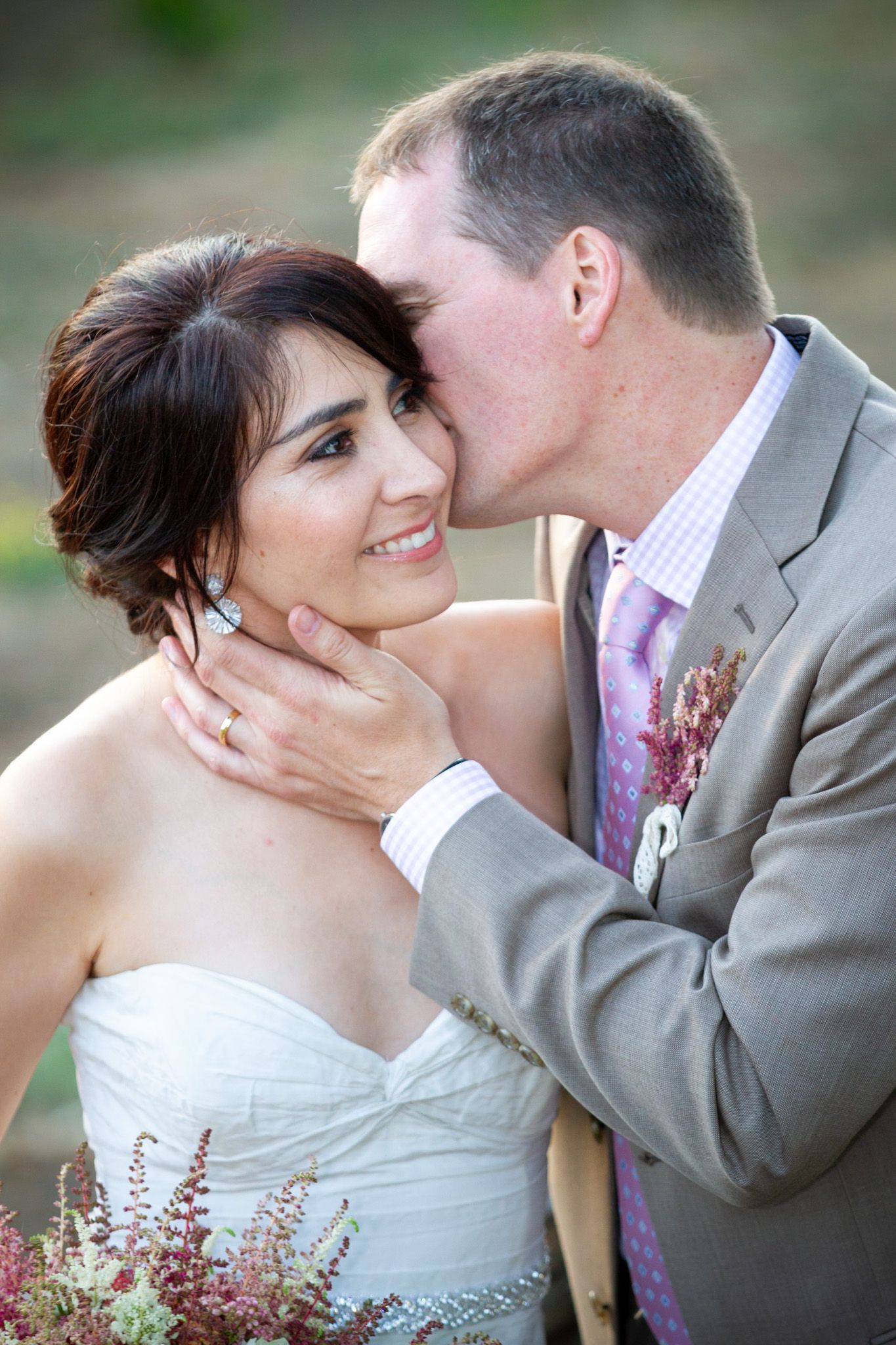 Tender moment captured between newlyweds in outdoor garden setting.
