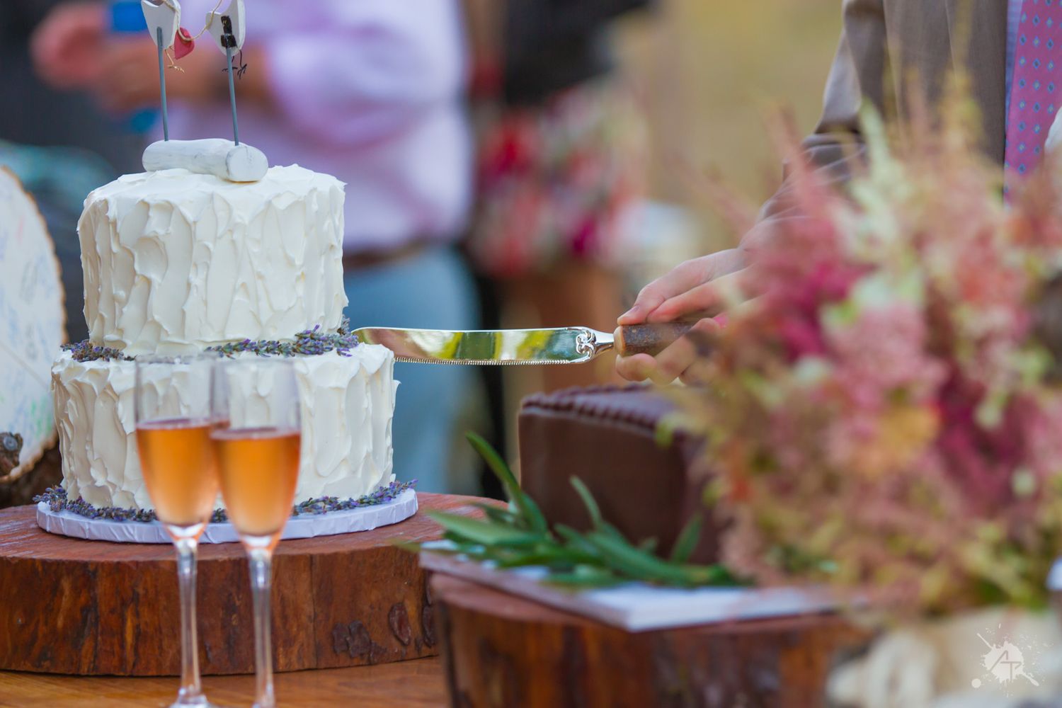 Wedding cake and champagne flutes displayed on wooden surface with floral decor.