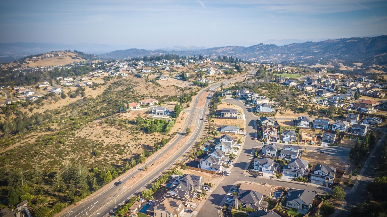 Aerial view of suburban housing development in arid hillside terrain.