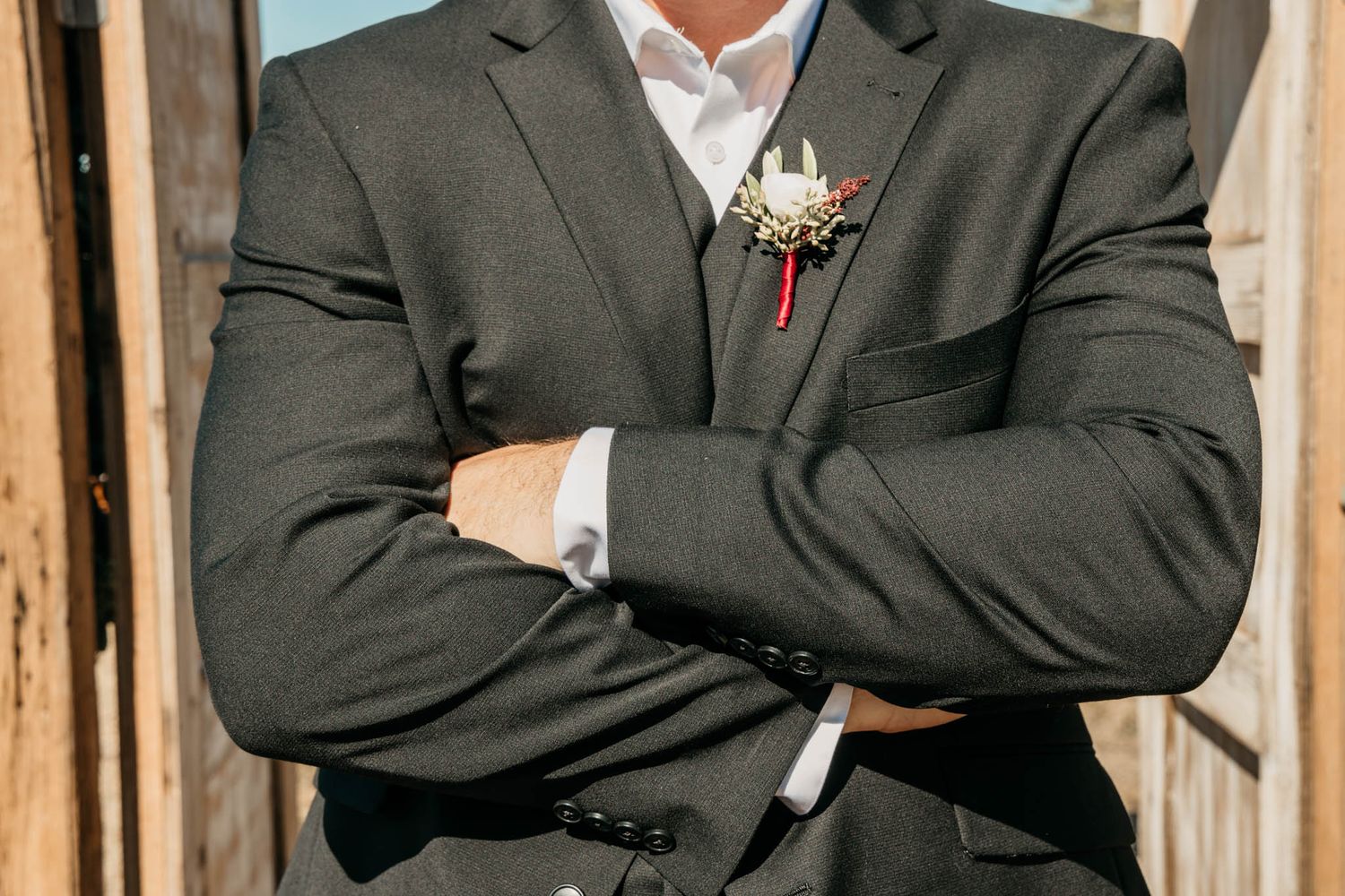 A formal suit with boutonniere photographed against wooden paneling.