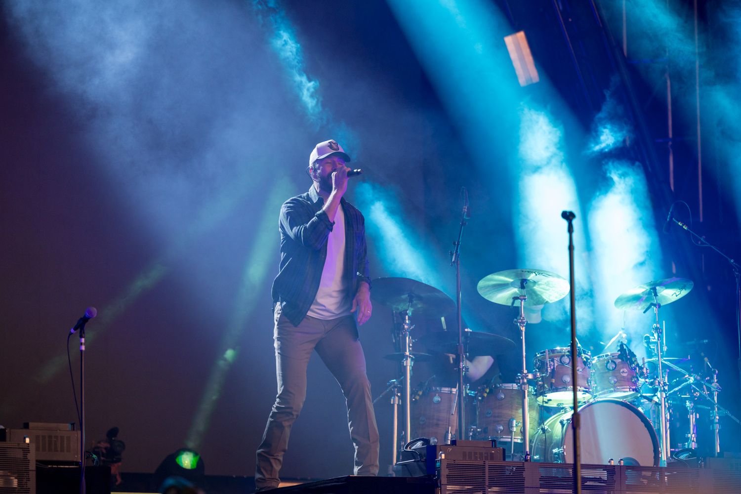 Rock band performs on stage with dramatic blue lighting and fog effects creating an atmospheric concert environment.