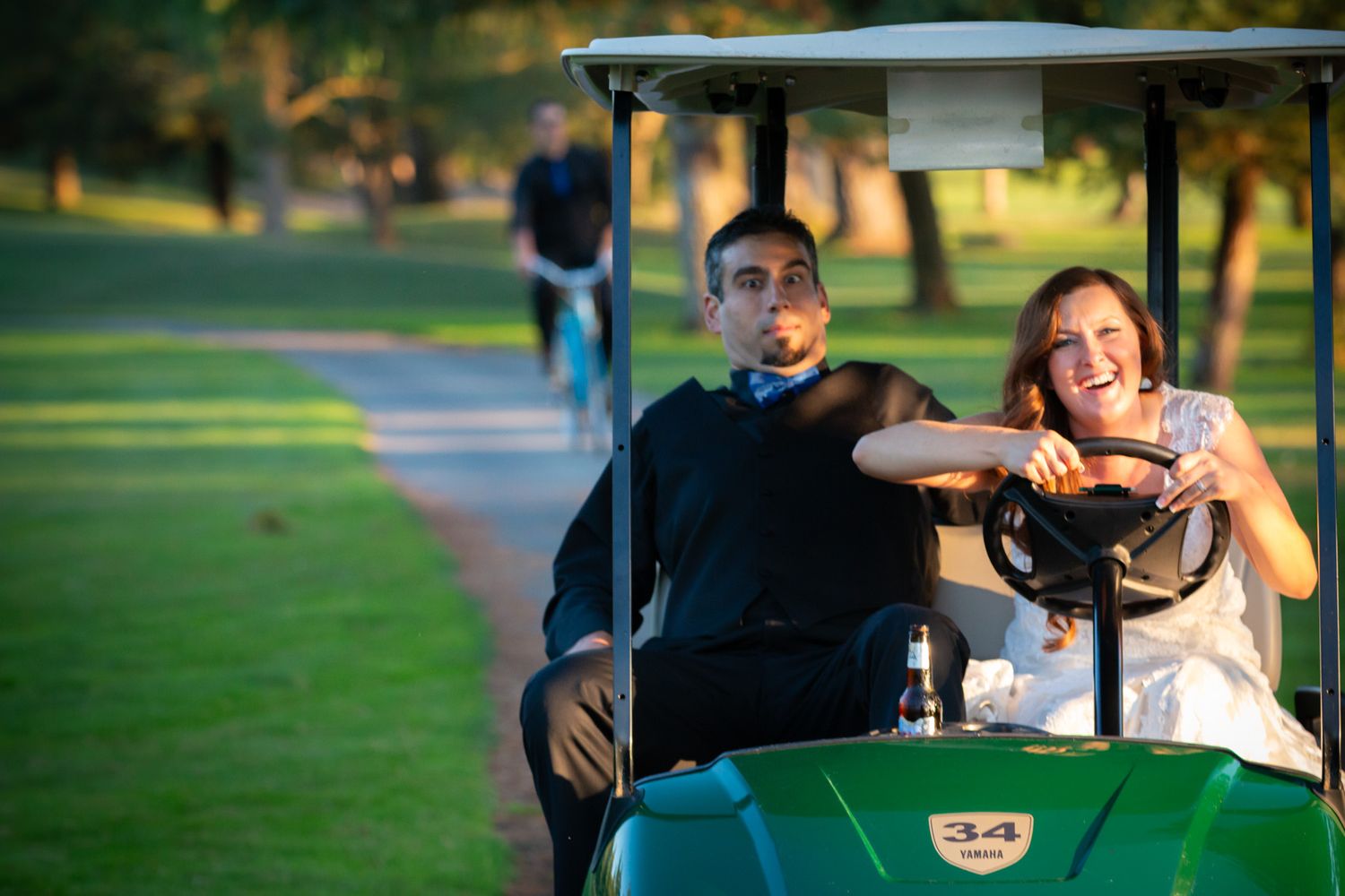 Newlyweds share a laugh while riding in a golf cart on their wedding day.