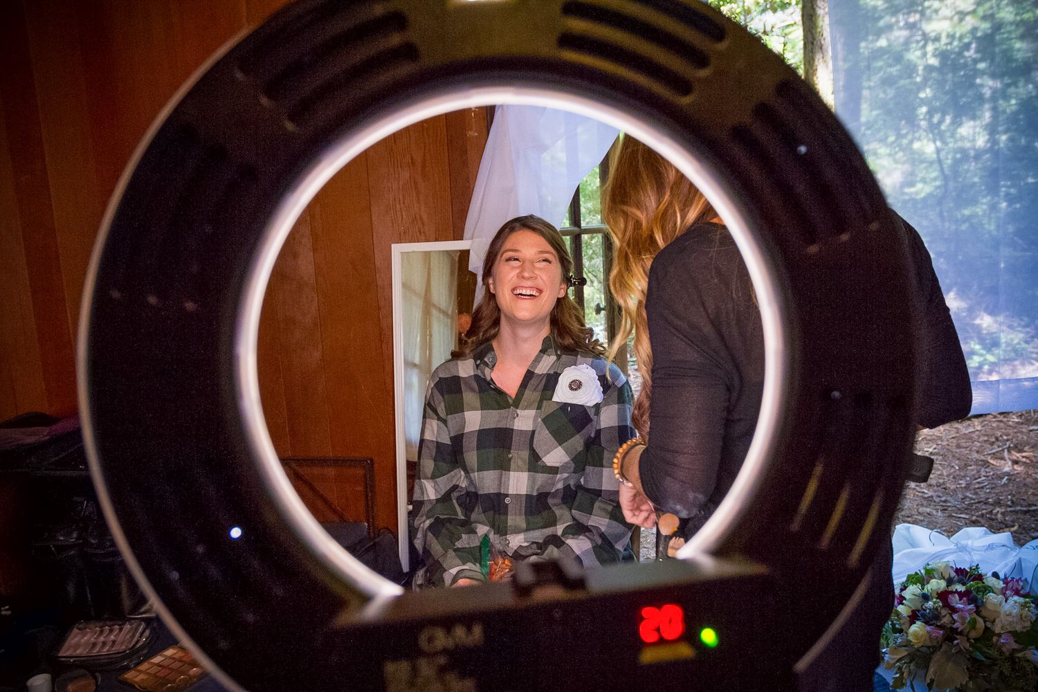 Behind the scenes shot of ring light illuminating someone during photo session.