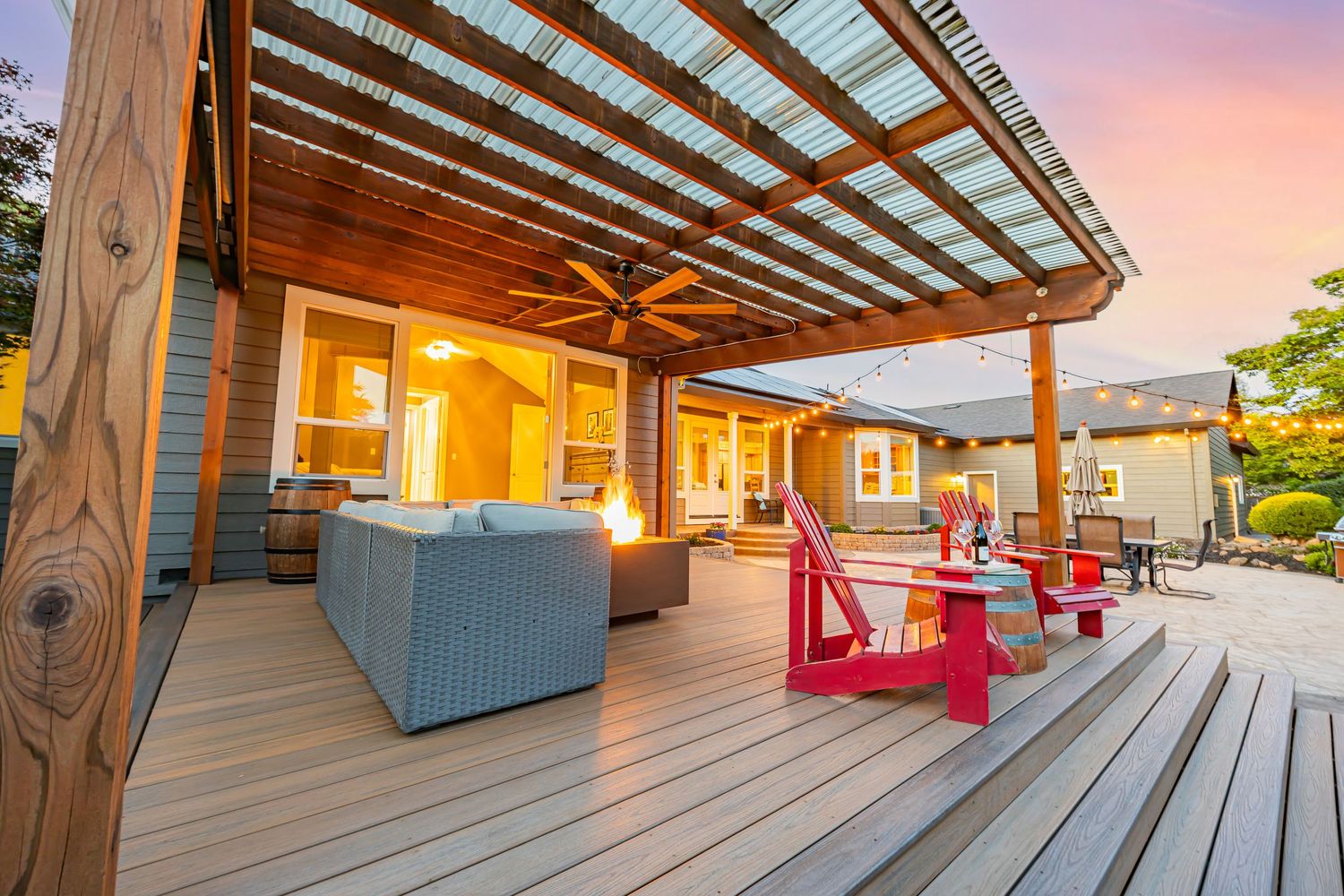 Covered deck with comfortable outdoor furniture and string lighting creates perfect evening entertainment space.
