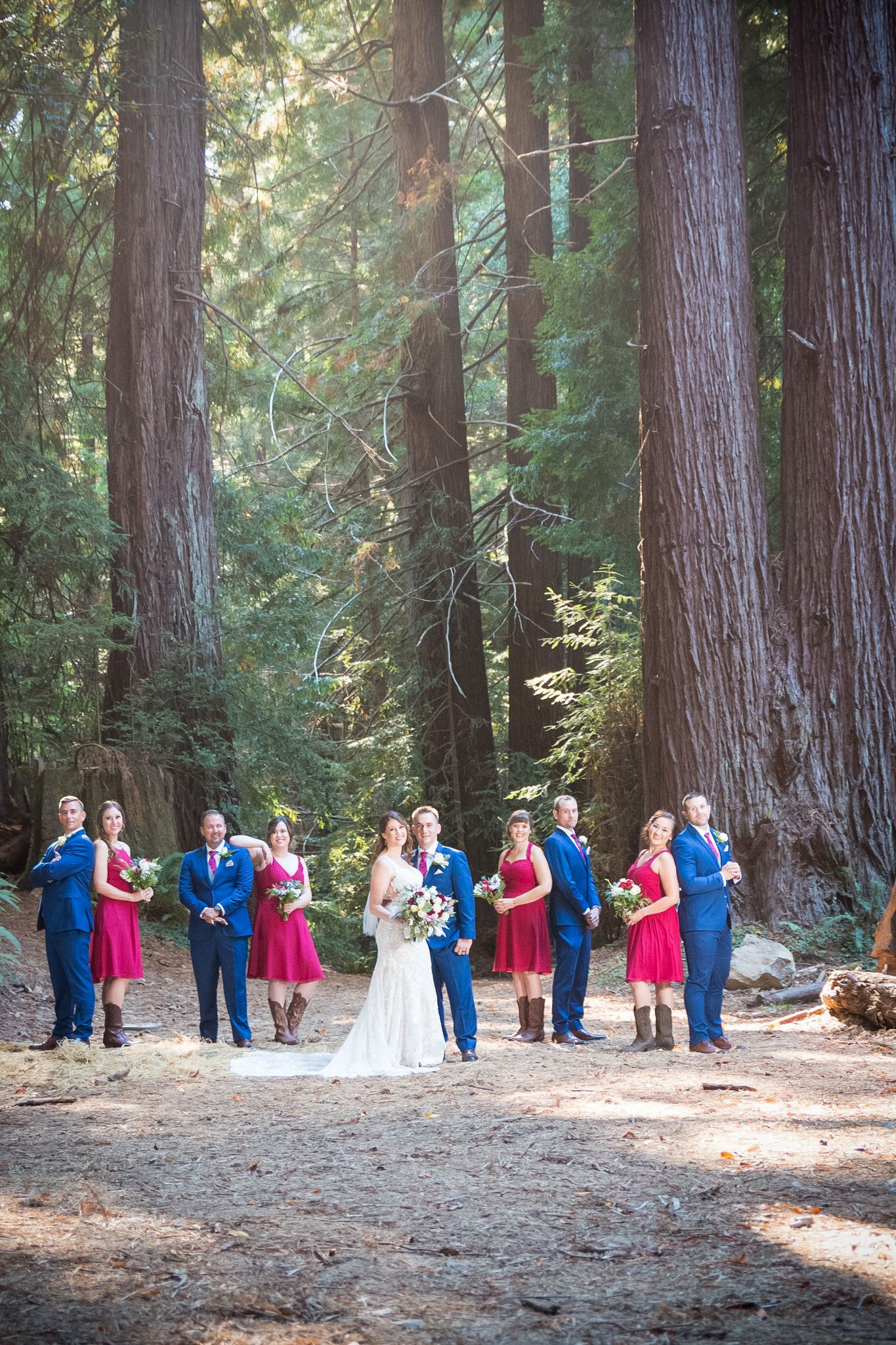 Wedding party arranged in symmetrical formation on forest path surrounded by towering redwood trees.