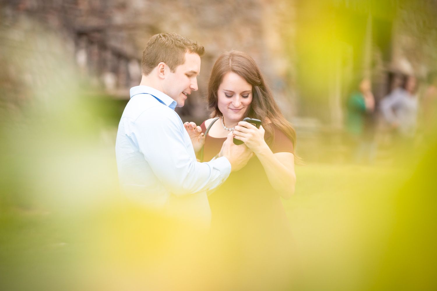 Romantic couple looking at something together while standing close in an outdoor setting.