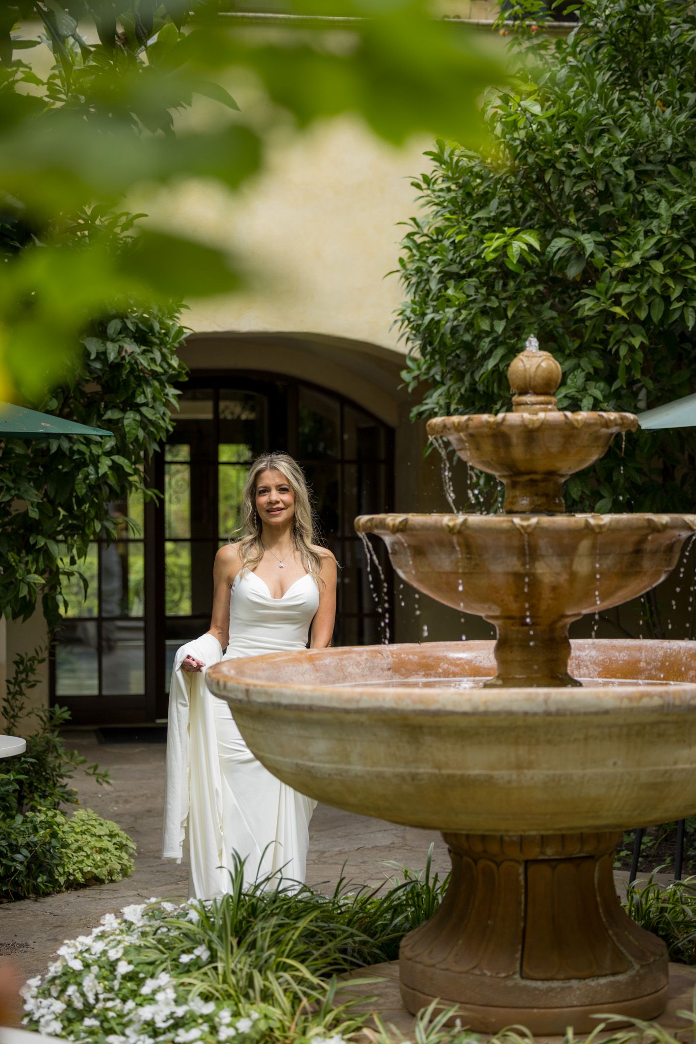 Elegant fountain surrounded by lush greenery in garden courtyard.