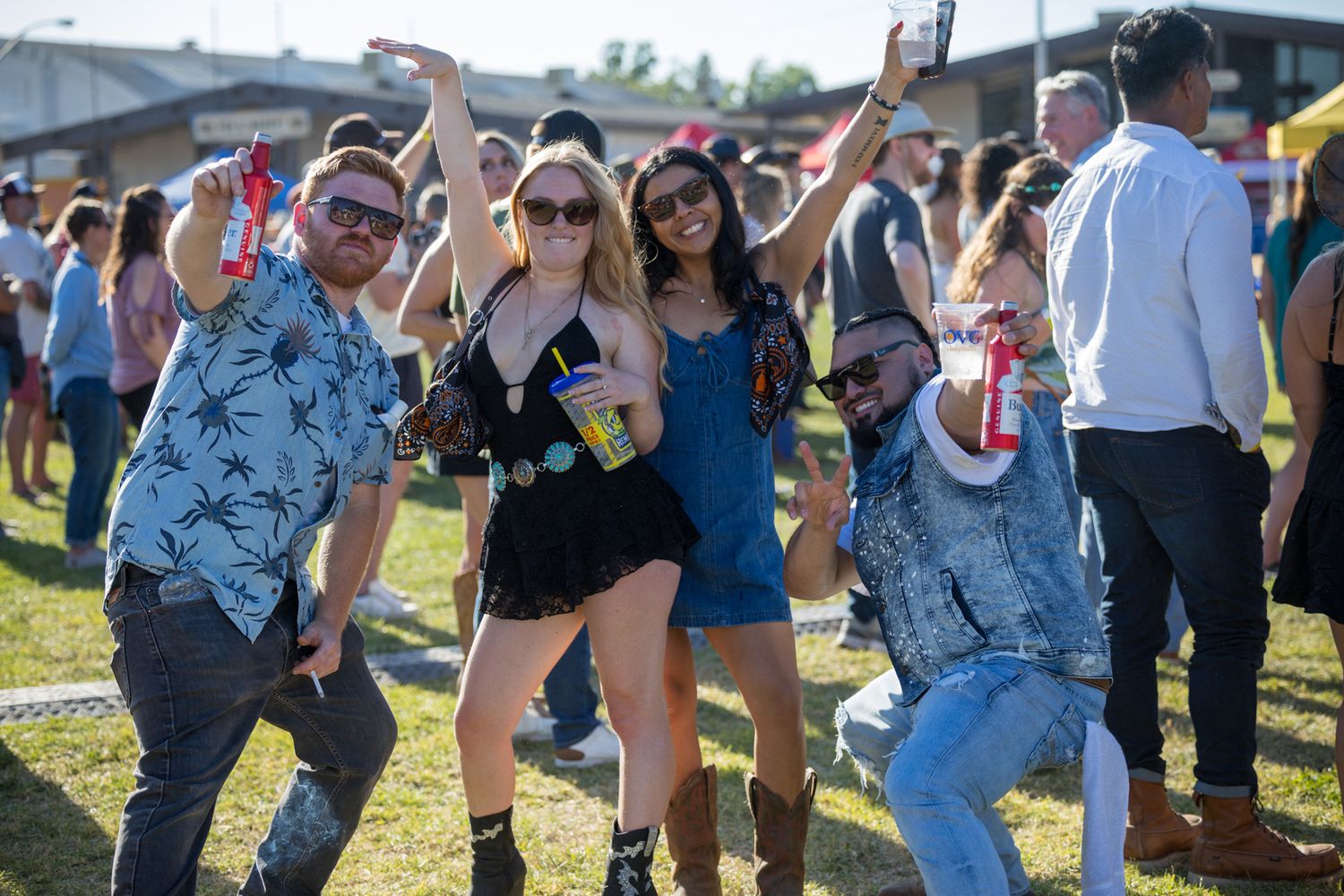 People dancing and having fun at an outdoor music festival or concert in sunny weather.