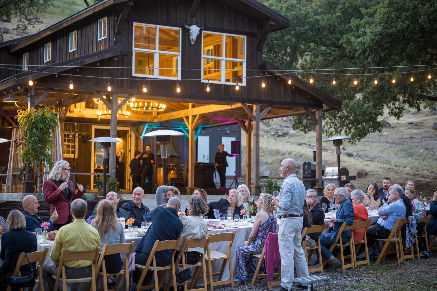 Guests dining outside a charming wooden lodge with string lights creating a warm ambiance.